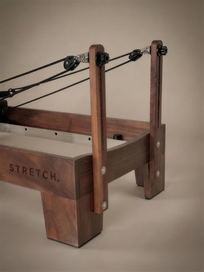 Achteraanzicht van de STRETCH walnut reformer met touwen en veersysteem